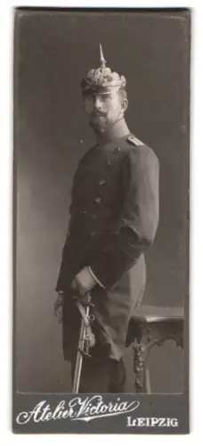 Fotografie Atelier Victoria, Leipzig, Leutnant im Überrock mit Pickelhaube und Säbel