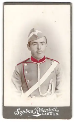 Fotografie Sophus Riberholt, Aarhus, dänischer Unteroffizier in Uniform mit Dienstmütze und Schärpe, tls. koloriert