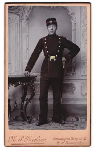 Fotografie N. P. Nielsen, Kjöbenhavn, Dronningens Tvergade 33, dänischer Soldat in Uniform mit Schirmmütze und Bajonett