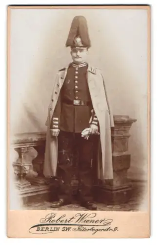 Fotografie Robert Wiener, Berlin, Jüterbogerstr. 9, Garde-Soldat in Uniform mit Mantel, Paradehelm und Bajonett