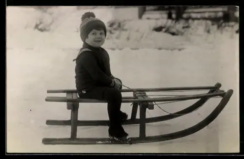 Foto-AK Kind mit Mütze auf einem Schlitten