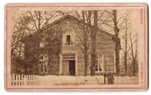Fotografie J. C. Angelbeck, Cuxhaven, Friedrichstrasse, unbekannter Ort, Gruppe am Zaun vor einem Wohnhaus