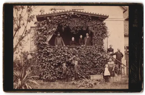 Fotografie Wilh. Duisdieker, Bünde i. W., unbekannter Ort, Gruppe mit Kindern bei einem berankten Hauseingang
