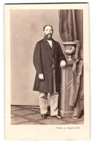 Fotografie L. Haase & Comp., Breslau, Tauentzienstr. 10, Herr im Anzug mit Podest