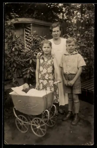 Foto-AK Mutter mit Kinderpaar u. Puppe im Puppenwagen in einem Garten