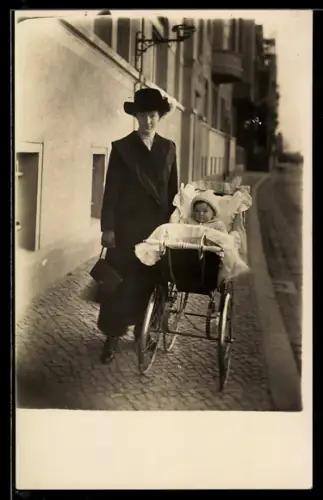 Foto-AK Leipzig-Gohlis, Mutter mit Kleinkind im Kinderwagen auf einem Bürgersteig, 1912