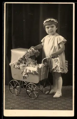 Foto-AK Kleines Mädchen mit Blumen-Haarband und blumengeschmücktem Puppenwagen
