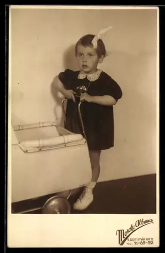 Foto-AK Kleines Mädchen mit Haarschleife schiebt einen Kinderwagen