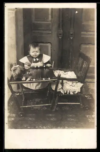 Foto-AK Kleinkind mit Puppe u. Plüschtier an einem Tischchen