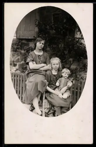 Foto-AK Zwei Mädchen mit Bubikopf-Puppe vor einem Gartenzaun