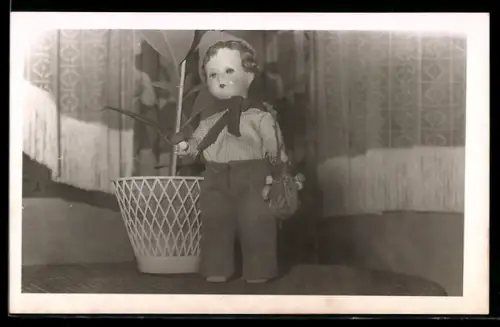 Foto-AK Puppe steht neben einer Grünpflanze