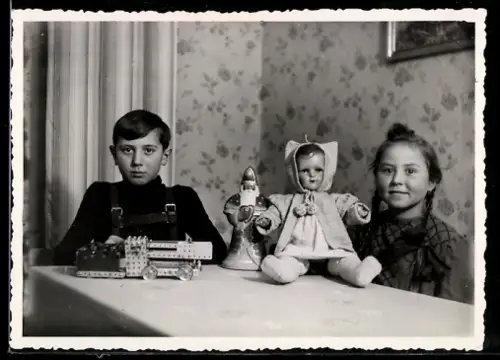 Foto-AK Kinder mit Puppe und Spielzeug an einem Tisch sitzend