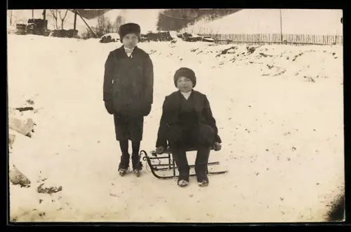 Foto-AK Kinder mit Schlitten in einem verschneiten Ort