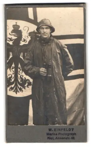 Fotografie W. Einfeldt, Kiel, Annenstr. 62, Matrose im Ölzeug mit Südwester und Fernglas vor Reichkriegsflagge