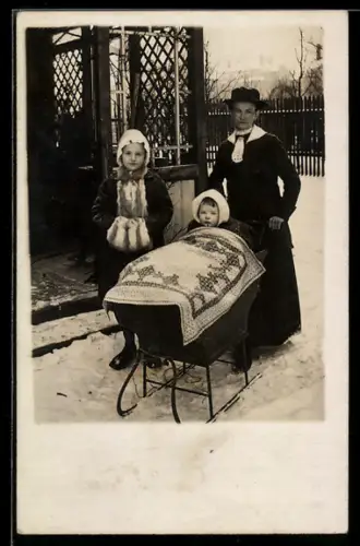 Foto-AK Frau mit Kind im Kinderwagen mit Kufen im Winter, Schlitten