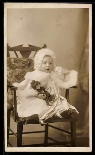 AK Kleines Mädchen im weissen Kleid mit Haube und Spielzeugpuppe