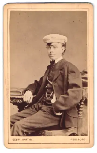 Fotografie Gebr. Martin, Augsburg, Bahnhofstrasse 22, Junger Student mit Tellermütze und Couleur im Porträt