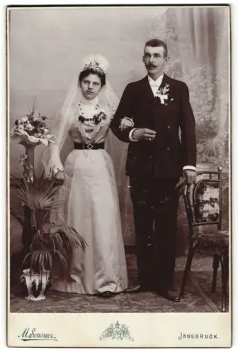 Fotografie M. Senoner, Innsbruck, Mariatheresiastrasse. 37, Hochzeitspaar mit Blumendekoration im Atelier