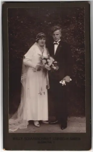 Fotografie Willy Schaarschmidt, Leipzig-Wahren, Blanksstr. 1, Hochzeitspaar mit Blumenstrauss vor einer Hecke