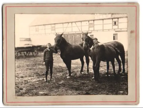 Fotografie unbekannter Fotograf und Ort, Zwei Jungen mit Pferden auf einem Gutshof
