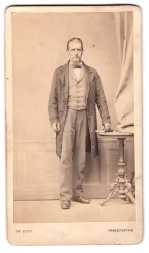 Fotografie Philipp Hoff, Frankfurt am Main, Bleicherstrasse 38, Herr im Anzug neben Tisch stehend