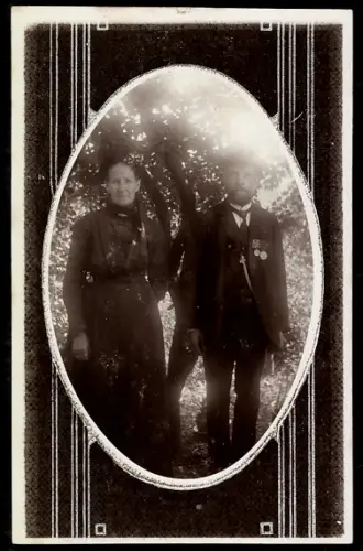 Foto-AK Ältere Dame und Herr mit Orden im Grünen, Ornament-Passepartout