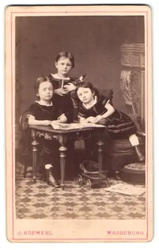Fotografie Julius Kosmehl, Magdeburg, Stephansbrücke 36, Drei Kinder mit Spielzeugen an einem Tisch