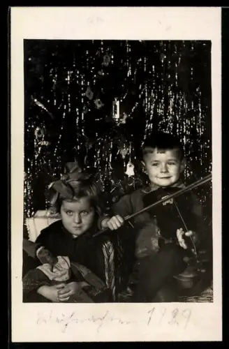 Foto-AK Glücklicher Knabe mit Geige u. Mädchen mit Puppe unter dem Weihnachtsbaum, 1929