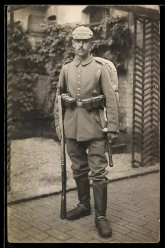 Foto-AK Soldat in Feldgrau Uniform mit Pickelhaube, Feldspaten, Patronentaschen und Gewehr 88