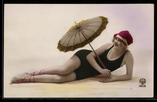 AK Hübsche Frau im Badeanzug und mit Sonnenschirm liegt auf dem Boden