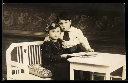 Foto-AK Zwei Kinder an einem Tisch mit Buch