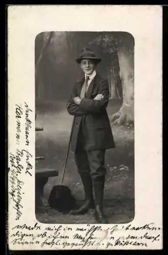 Foto-AK Junger Mann im Mantel und mit Hund vor Studiokulisse eines Waldes