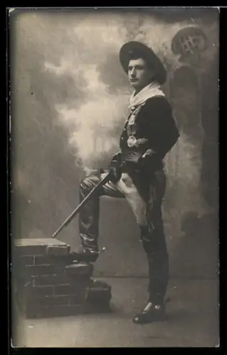 Foto-AK Mann mit Gewehr und Sporenstiefeln vor einer Studiokulisse