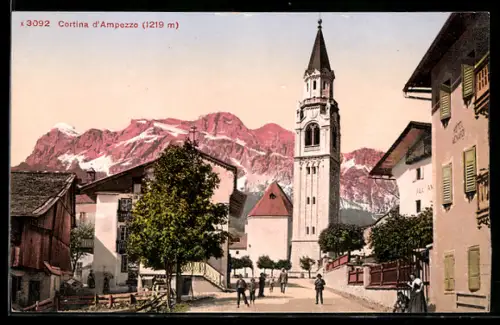 AK Cortina D`Ampezzo, Strassenpartie mit Blick nach der Kirche und Dolomiten in der Dämmerung