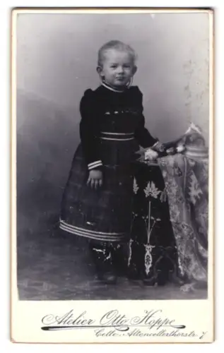 Fotografie Atelier Otto Hoppe, Celle, Altencellerthorstr. 7, Martha als Kind im dunklen Kleid neben Tisch