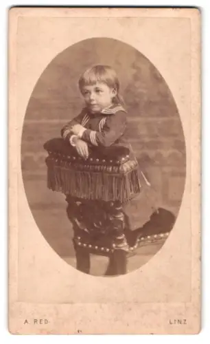 Fotografie August Red, Linz, Landstrasse, Johanna Nebinger auf gepolstertem Stuhl sitzend, geb. 1899