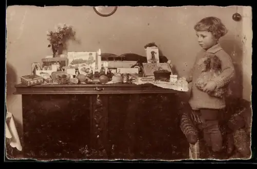 Foto-AK Junges Kind mit Spielzeughund vor einem Tisch mit weiteren Spielsachen