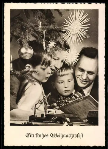 AK Familie unter einem Weihnachtsbaum mit einem Spielzeugkran aus Blech