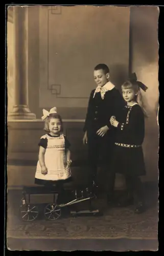 Foto-AK Drei Kinder mit einem Spielzeugpferd