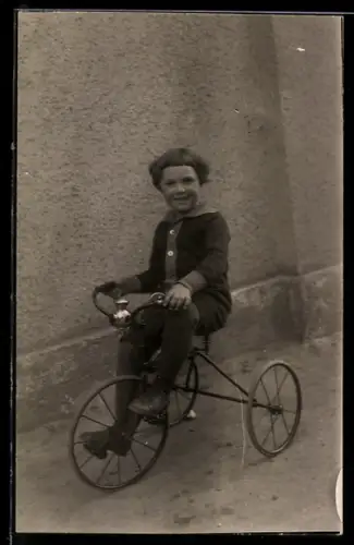 Foto-AK Junges lächelndes Kind auf einem Dreirad