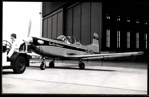 Fotografie Flugzeug Pilatus PC-7 Turbo Trainer Kennung HB-HOZ mit schlepper vor Hangar