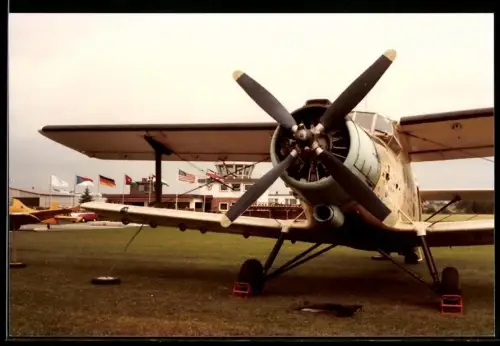 Fotografie Flugzeug Antonow An-2, Doppeldecker auf einem Flughafen, Tower im Hintergrund