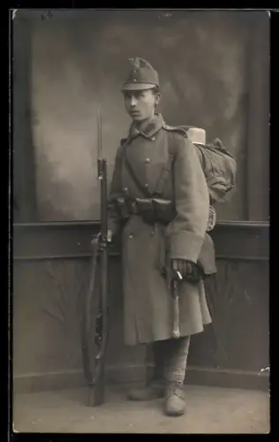 Foto-AK Porträt eines österreichischen Soldaten in Uniform mit Waffe
