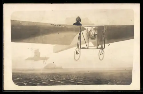 Foto-AK Mann mit Fliegerhaube sitzt in einer Flugzeugkulisse über dem Meer