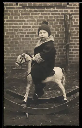 Foto-AK Kind in Winterkleidung auf einem Schaukelpferd