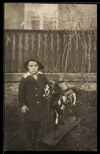 Foto-AK Junge im Mantel mit Spielzeugpferd