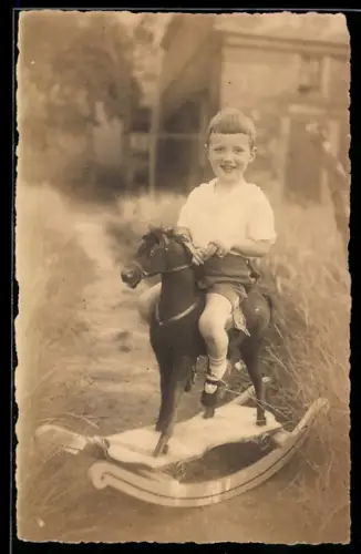 AK Lächelnder Junge auf einem Schaukelpferd sitzend