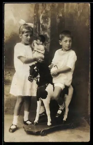 Foto-AK Geschwister mit Pferdespielzeug auf Rollen und Puppe
