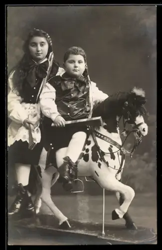 AK Zwei Kinder auf einem Spielzeugpferd auf Rollen, Trockenstempel Cöln-Nippes