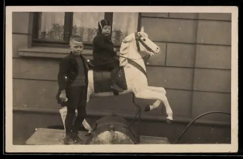 AK Zwei Kinder mit Schaukelpferd vor einem Haus